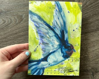 May include: A rectangular art print featuring a blue bird in flight against a vibrant lime green background. The composition incorporates collage elements of musical staff notation and notes, with the artist signature Isa Graze visible.