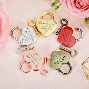 May include: A collection of heart-shaped padlocks in various colours, including gold and silver, each with a key. The padlocks are engraved with names, dates, and phrases such as "I will love you forever" and "Happy 5 Year Wedding Anniversary."