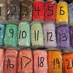 May include: A collection of twenty rolls of elastic cord in various colors, each individually wrapped in clear plastic. The rolls are numbered from 1 to 20 in black marker. Colors include brown, gray, red, yellow, blue, green, purple, and orange.