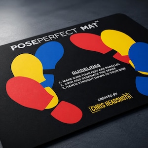 May include: A black rectangular PosePerfect Mat featuring colorful red, yellow, and blue foot-shaped icons arranged in a circular pattern. The mat includes white text with guidelines for posing and the branding text Created by Chris Headshots.