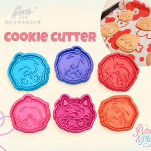 May include: A set of six plastic cookie cutters featuring stylized character faces in blue, purple, red, pink, magenta, and orange. The text LOVE AND DEEPSPACE COOKIE CUTTER is printed above the cutters, and a circular inset shows baked cookies.