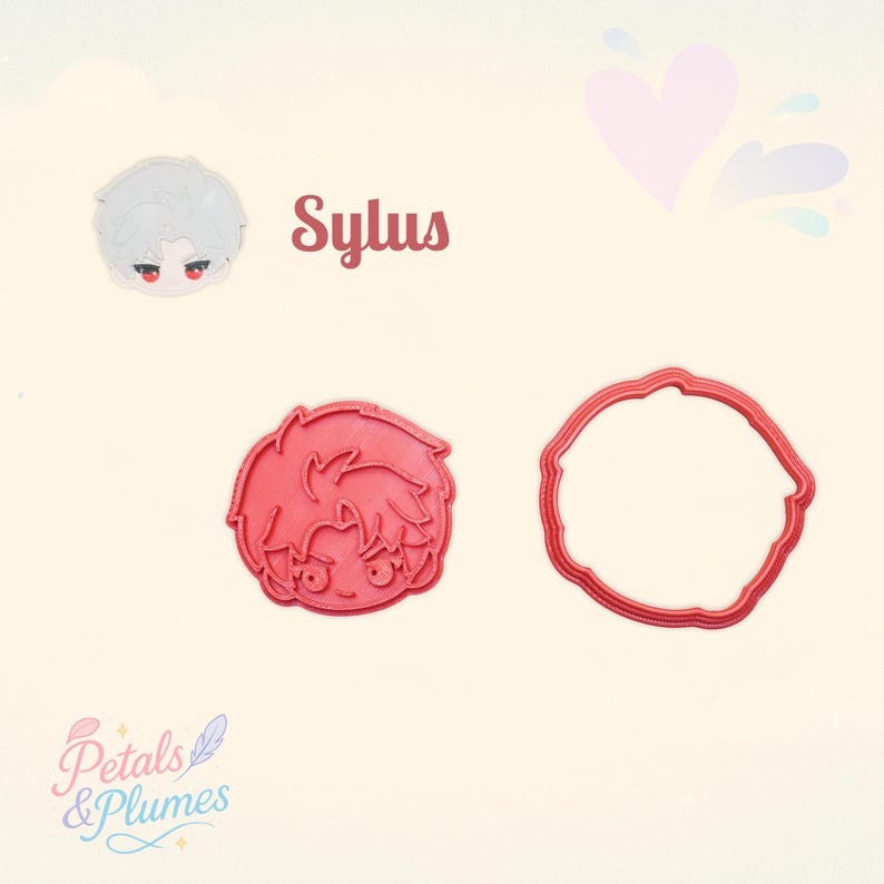 May include: A red plastic cookie cutter set featuring a stylized character head with spiky hair and large eyes, accompanied by a matching circular outline cutter. The text Sylus is printed in brown above the character illustration.