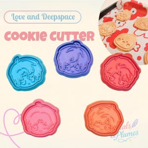 Op de afbeelding: Een verzameling kleurrijke koekjessnijders in blauw, paars, rood, roze en oranje, elk in de vorm van een cartoongezicht. De woorden "Love and Deepspace" en "cookie cutter" staan in de afbeelding. Gebakken koekjes zijn zichtbaar op de achtergrond.