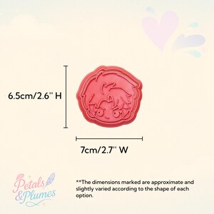 May include: A red plastic cookie cutter shaped like an anime-style character head with spiky hair. The cutter measures 6.5 inches in height and 7 inches in width. The text Petals & Plumes is visible in the corner along with a disclaimer about dimensions.