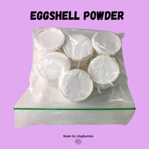 May include: A clear plastic bag containing six white, circular eggshell powder discs. The bag is sealed with a green zipper. The text "EGGSHELL POWDER" is printed at the top. The text "Made by AlagbaOmi" is at the bottom.