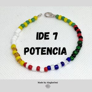 May include: A beaded bracelet with a variety of colors, including yellow, white, red, blue, and green. The bracelet has a silver clasp and the text "IDE 7 POTENCIA" in black. The bracelet is made by AlagbaOmi.