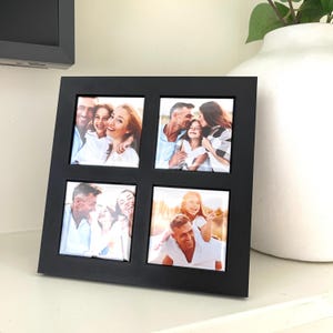 Peut inclure: Un cadre photo carr&eacute; noir avec quatre ouvertures, chacune affichant une photo de famille. Les photos montrent des personnes souriantes dans diverses poses. Le cadre est pos&eacute; sur une surface blanche, avec un vase blanc et de la verdure en arri&egrave;re-plan.