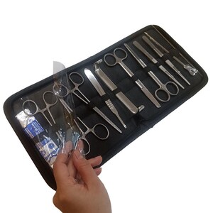 Op de afbeelding: Een zwarte etui met ritssluiting bevat een set chirurgische instrumenten van roestvrij staal, waaronder diverse scharen, pincetten en sondes, georganiseerd in elastische lussen. Een doorzichtig plastic beschermvel bedekt een deel van de instrumenten.