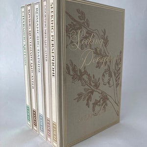 May include: A set of five hardcover books with beige fabric covers and gold foil lettering. The titles include Seeking Persephone, Courting Miss Lancaster, Romancing Daphne, Loving Lieutenant Lancaster, and Charming Artemis, all published by Eden.