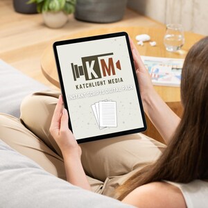 Op de afbeelding: Een zwarte tablet met het logo "Katchlight Media Instant Scripts Digital Pack" en pictogrammen van stapels papier. De tablet wordt vastgehouden door een persoon die op een grijze bank zit. Het logo bevat de letters "KM" in een bruin en rood kleurenschema.
