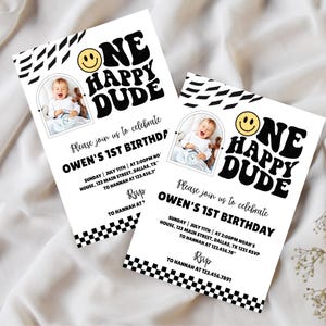 Könnte beinhalten: Zwei weiße Einladungen mit schwarzem Text und einem Foto eines Babys. Die Einladungen tragen die Aufschrift "ONE HAPPY DUDE" mit einem Smiley. Der Text enthält "OWEN'S 1ST BIRTHDAY" und RSVP-Informationen.
