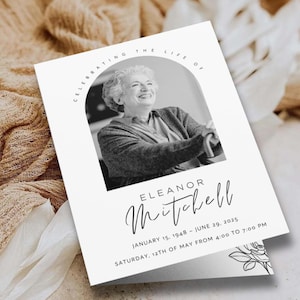 Könnte beinhalten: Eine weiße Trauerkarte mit einem Schwarz-Weiß-Foto einer lächelnden Frau. Die Karte trägt die Aufschrift "Celebrating the Life of Eleanor Mitchell" mit Daten und Uhrzeiten. Ein Blumendesign befindet sich in der Ecke.
