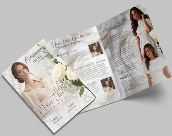 Op de afbeelding: Een herdenkingsprogramma in wit en crème. Het bevat foto's, tekst en bloemaccenten. De cover luidt "Celebrating the Life & Legacy of Marie Elve". Binnenin staan ​​huldebetuigingen, een gebed en foto's.