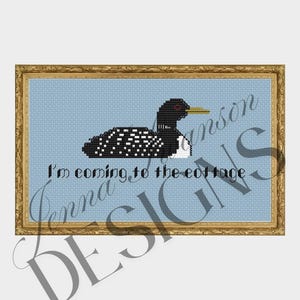 May include: Cross-stitch art of a loon with black, white, and red details, set against a light blue background. The text "I'm coming to the cottage" is below the bird. The artwork is framed in a gold-colored frame.