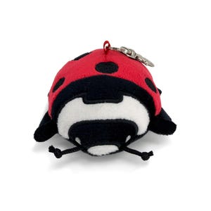 Peut inclure: Un porte-cl&eacute;s coccinelle en peluche. Le corps rouge est orn&eacute; de points noirs, avec des d&eacute;tails noirs et un visage blanc et noir. Il est &eacute;quip&eacute; d'un fermoir en m&eacute;tal argent&eacute; et d'une petite boucle rouge pour l'attacher.