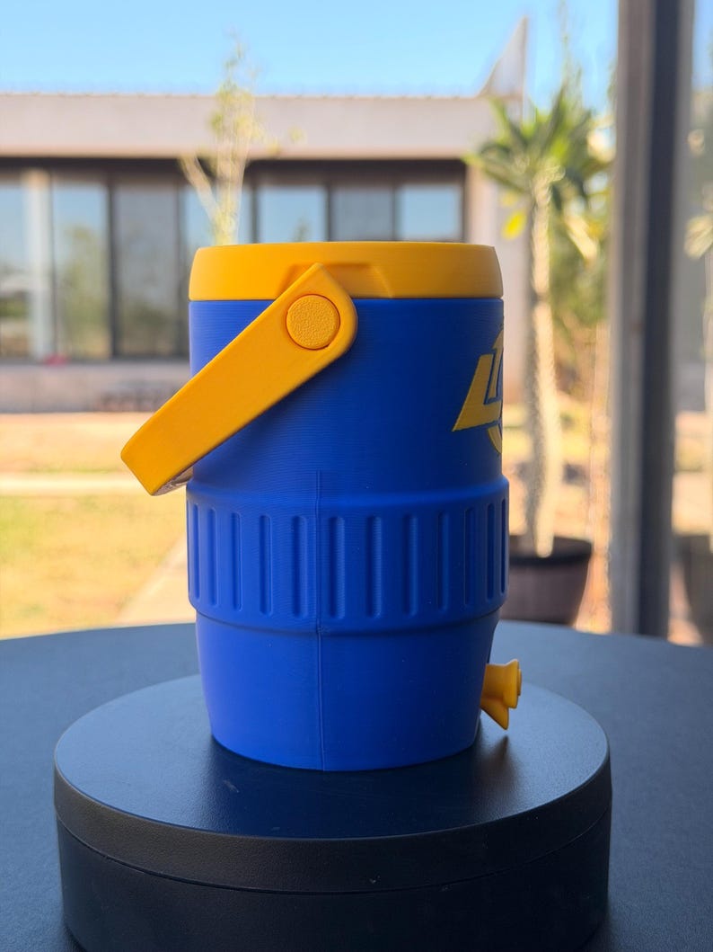 May include: A blue and yellow water cooler with a yellow handle and spout. The cooler has a cylindrical shape with a yellow lid and a blue body. The cooler has the number 4 printed on the side in yellow.