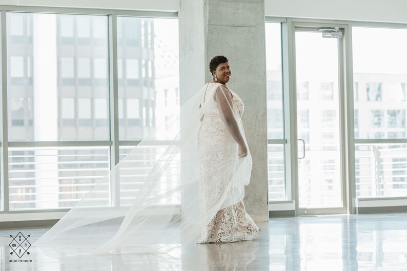 A pair of detachable cape veil  attached to either shoulder. They are an asymmetrical cascading shape. Shown in Lt Ivory.