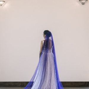 A single-layer oval shape veil made from a lightweight, ultra soft tulle covered in pearl stud beads. Shown in Royal Purple.