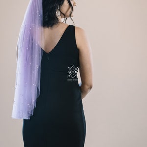 A single-layer oval shape veil made from a lightweight, ultra soft tulle covered in pearl stud beads. Shown in Wisteria.