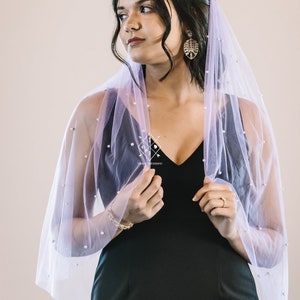 A single-layer oval shape veil made from a lightweight, ultra soft tulle covered in pearl stud beads. Shown in Wisteria.