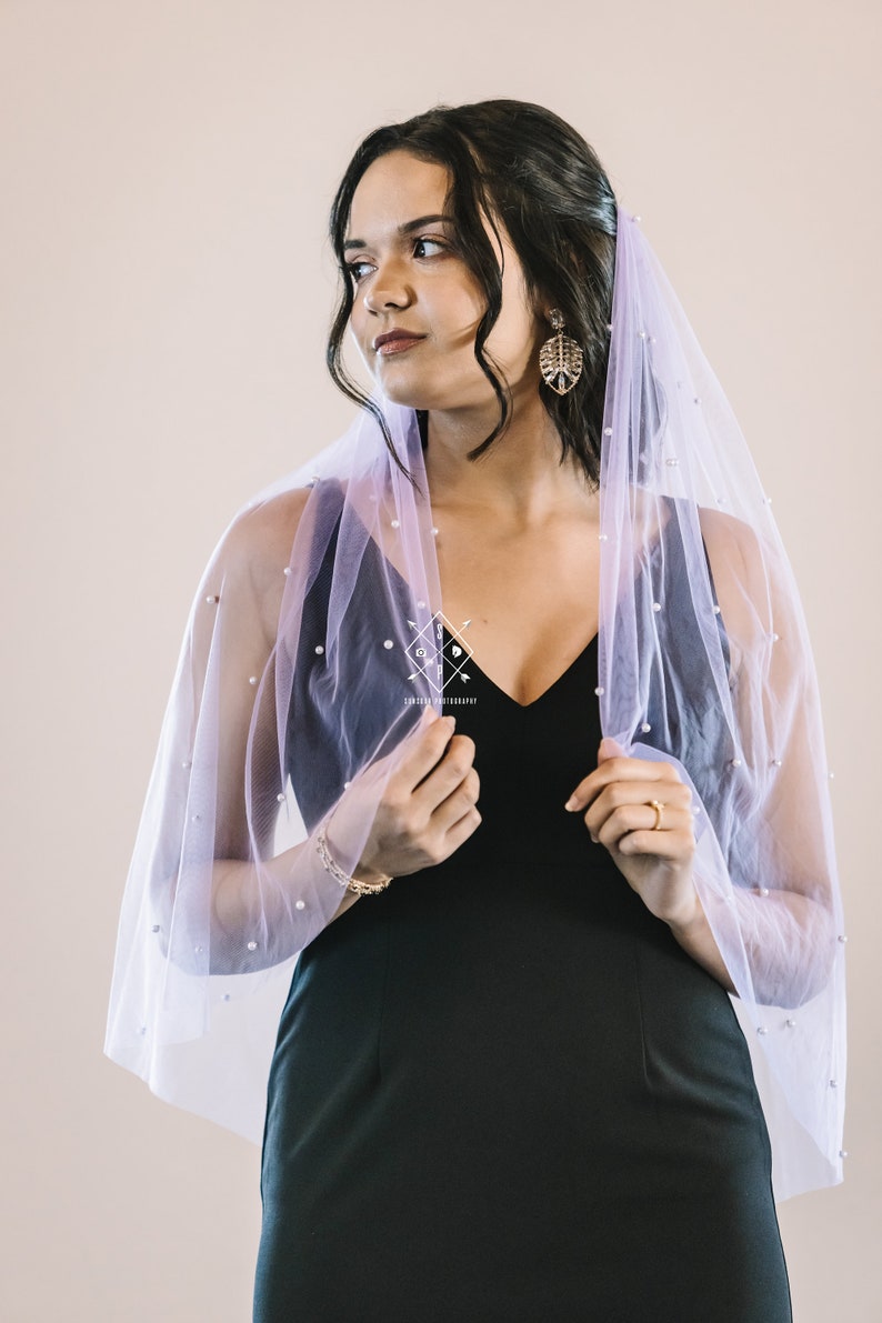 A single-layer oval shape veil made from a lightweight, ultra soft tulle covered in pearl stud beads. Shown in Wisteria.
