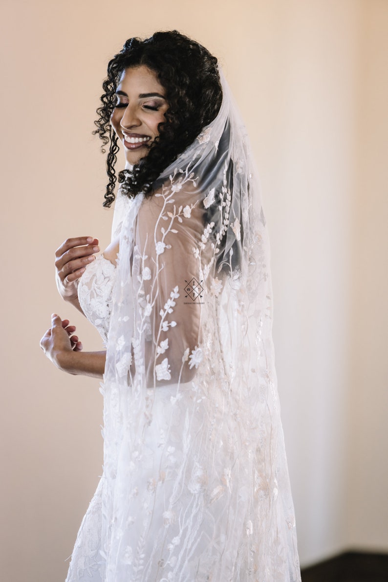 A single-layer oval veil made from a ivory floral embroidered lace on a light ivory tulle.