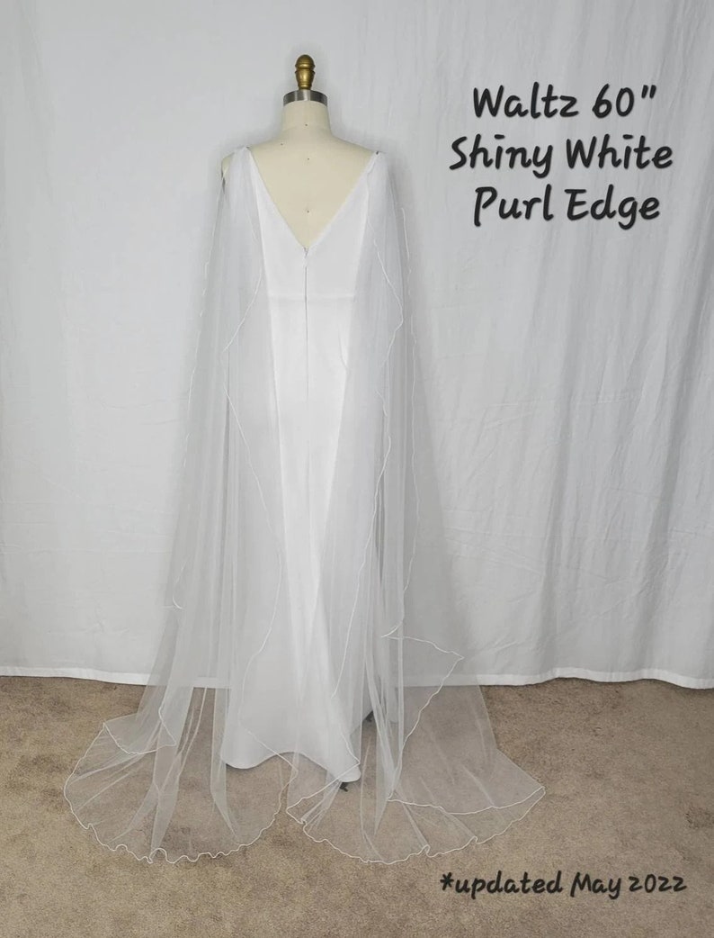 A pair of detachable cape veil  attached to either shoulder. They are an asymmetrical cascading shape. Shown in Shiny White.