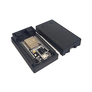 Könnte beinhalten: Ein schwarzes, 3D-gedrucktes rechteckiges Gehäuse mit separatem Deckel, das ein ESP32-Entwicklungsboard enthält. Die Platine verfügt über ein metallisch silbernes quadratisches Modul, einen Micro-USB-Anschluss, zwei kleine Tasten und Bauteile.