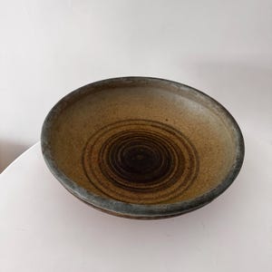 Op de afbeelding: Een set van drie keramische mokken met een gespikkelde, matte afwerking. De mokken zijn in crème, lichtgrijs en donkergrijs. Elke mok heeft een eenvoudig, minimalistisch ontwerp.