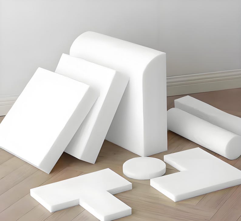 May include: An assortment of white foam shapes, including rectangular, cylindrical, and curved pieces. The collection features a variety of sizes and forms, suitable for various applications. The shapes are arranged on a light-colored wooden floor.