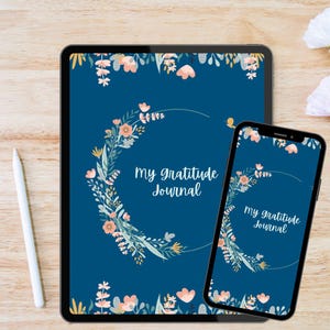 May include: A digital tablet and smartphone show a floral design with the text "My gratitude Journal" on a dark blue background. The floral design includes pink, yellow, and white flowers and green leaves. A white stylus is on the left.