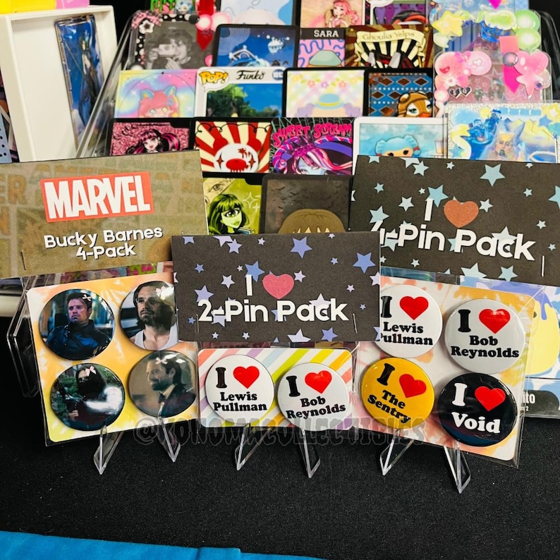 May include: A display of various pin packs and individual pins. The packs include "Marvel Bucky Barnes 4-Pack" and "2-Pin Pack" with star and heart designs. Individual pins feature text like "I Lewis Pullman" and "I Bob Reynolds."