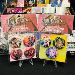 May include: Two packs of Lollipop Chainsaw pin sets. One pack is a 4-pin pack and the other is a 3-pin pack. The pins feature colorful character art. The packaging has the Lollipop Chainsaw logo and rainbow design.