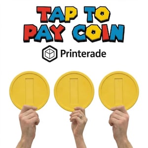 Puede incluir: Tres monedas amarillas con un diseño rectangular se sostienen sobre un fondo blanco. El texto "TAP TO PAY COIN" se muestra encima de las monedas en rojo, azul y amarillo. También es visible el logotipo de "Printerade".