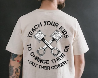 Op de afbeelding: Crèmekleurig T-shirt met een zwart-witte afbeelding van gekruiste zuigers en de tekst "TEACH YOUR KIDS TO CHANGE THEIR OIL *NOT THEIR GENDER*". Het T-shirt heeft een ronde hals en korte mouwen.