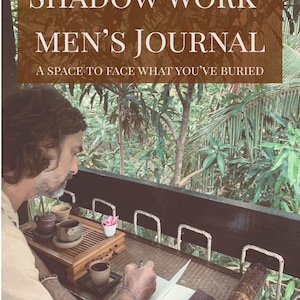 以下が含まれることがあります： 「Shadow Work Men's Journal」というテキストと「A space to face what you've buried」というキャッチコピーが入ったジャーナル。画像には、お茶セットのあるテーブルでジャーナルに書き込んでいる人が写っており、背景は緑豊かな風景です。