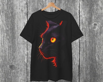 May include: Black t-shirt featuring a side profile of a black cat with glowing orange eyes and red outlining. The cat's silhouette is set against a dark background. The shirt is hanging on a wooden hanger.