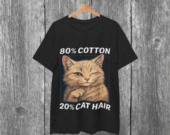 May include: Black t-shirt with a winking cat graphic. The text above the cat reads "80% COTTON", and below the cat, the text reads "20% CAT HAIR". The cat is light brown and tan, with a blue border.