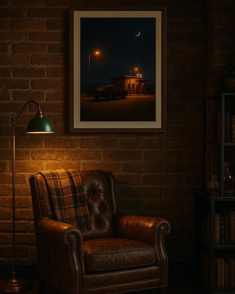 May include: A framed print depicts a nighttime scene with a gas station, car, and crescent moon. A brown leather armchair with a plaid throw sits beneath the print. A green lamp with a brass stand is to the left.