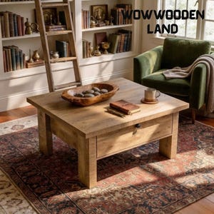 May include: A square light brown wooden coffee table with a single drawer and a black knob. On the table sits a wooden bowl filled with smooth stones, a small brown notebook, and a ceramic mug. The text WOWWOODEN LAND is visible in the corner.