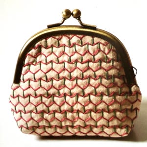 Peut inclure: Un petit porte-monnaie beige avec une fermeture à fermoir. Le sac est orné d'un motif géométrique de coutures rouges et vertes. Le cadre et le fermoir en métal sont de couleur bronze.