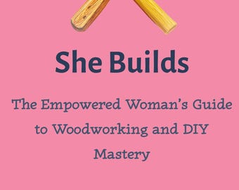 May include: A pink background with a crossed hammer and paintbrush. The text "She Builds" is above "The Empowered Woman's Guide to Woodworking and DIY Mastery" and the author's name. The bottom text reads "Third Shift Crafts".