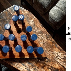 May include: A wooden board game with a triangular peg pattern. The board is stained with a pecan finish and features blue plastic pegs. The text on the side reads "Pine Stained with Pecan and Blue Plastic Dowels."
