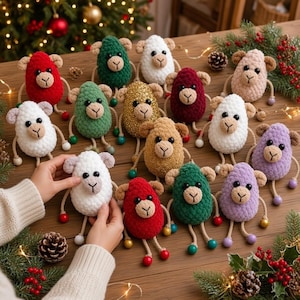 Peut inclure: Une collection de petits moutons en crochet de différentes couleurs, notamment rouge, vert, blanc, doré, marron et violet. Chaque mouton présente un corps rond, de petites oreilles, des yeux noirs et des pattes pendantes avec des perles colorées.