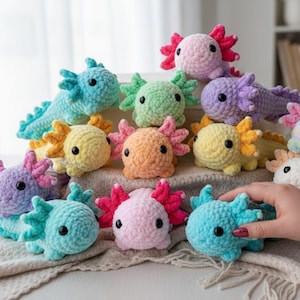 May include: A collection of small, plush axolotl toys made from soft, textured yarn in various pastel colors including pink, blue, yellow, green, and purple. Each stuffed animal features prominent external gills, round black eyes, and a small tail.