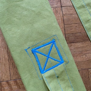 May include: A green canvas yoga mat bag with a blue embroidered X on the front.