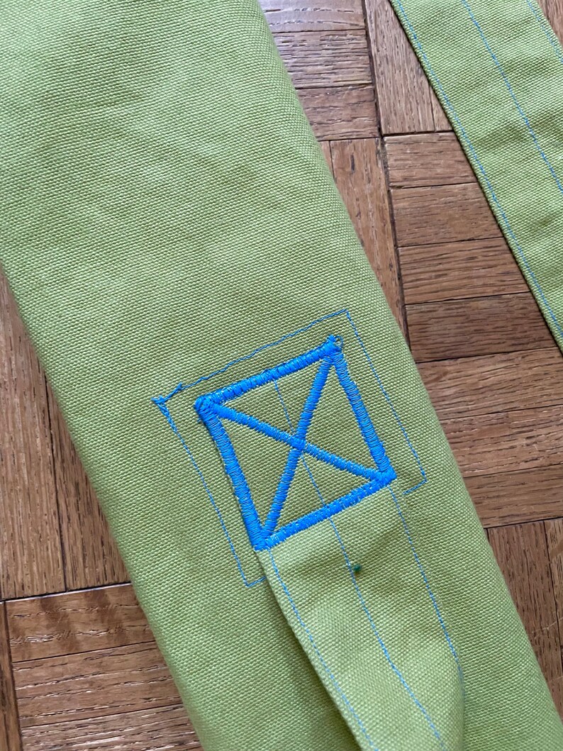 May include: A green canvas yoga mat bag with a blue embroidered X on the front.