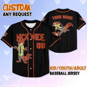 Op de afbeelding: Zwart honkbalshirt met oranje rand, met een cartoon vos karakter. De voorkant toont "NICK WILDE" en het nummer "00". De achterkant heeft "YOUR NAME". Tekst bovenaan zegt "CUSTOM ANY REQUEST". De onderste tekst zegt "KID/YOUTH/ADULT BASEBALL JERSEY".