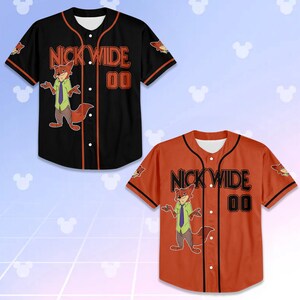 Op de afbeelding: Twee honkbalshirts, &eacute;&eacute;n zwart en &eacute;&eacute;n oranje, met een cartoon vos-personage. De shirts hebben de tekst "NICK WIDE 00". Het zwarte shirt heeft oranje afwerking, en het oranje shirt heeft zwarte afwerking.