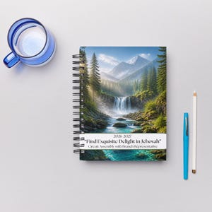 May include: A spiral-bound notebook featuring a landscape illustration of a waterfall, forest, and mountains. The cover text reads 2026-2027 "Find Exquisite Delight in Jehovah" Circuit Assembly with Branch Representative. A blue mug and two pencils are nearby.